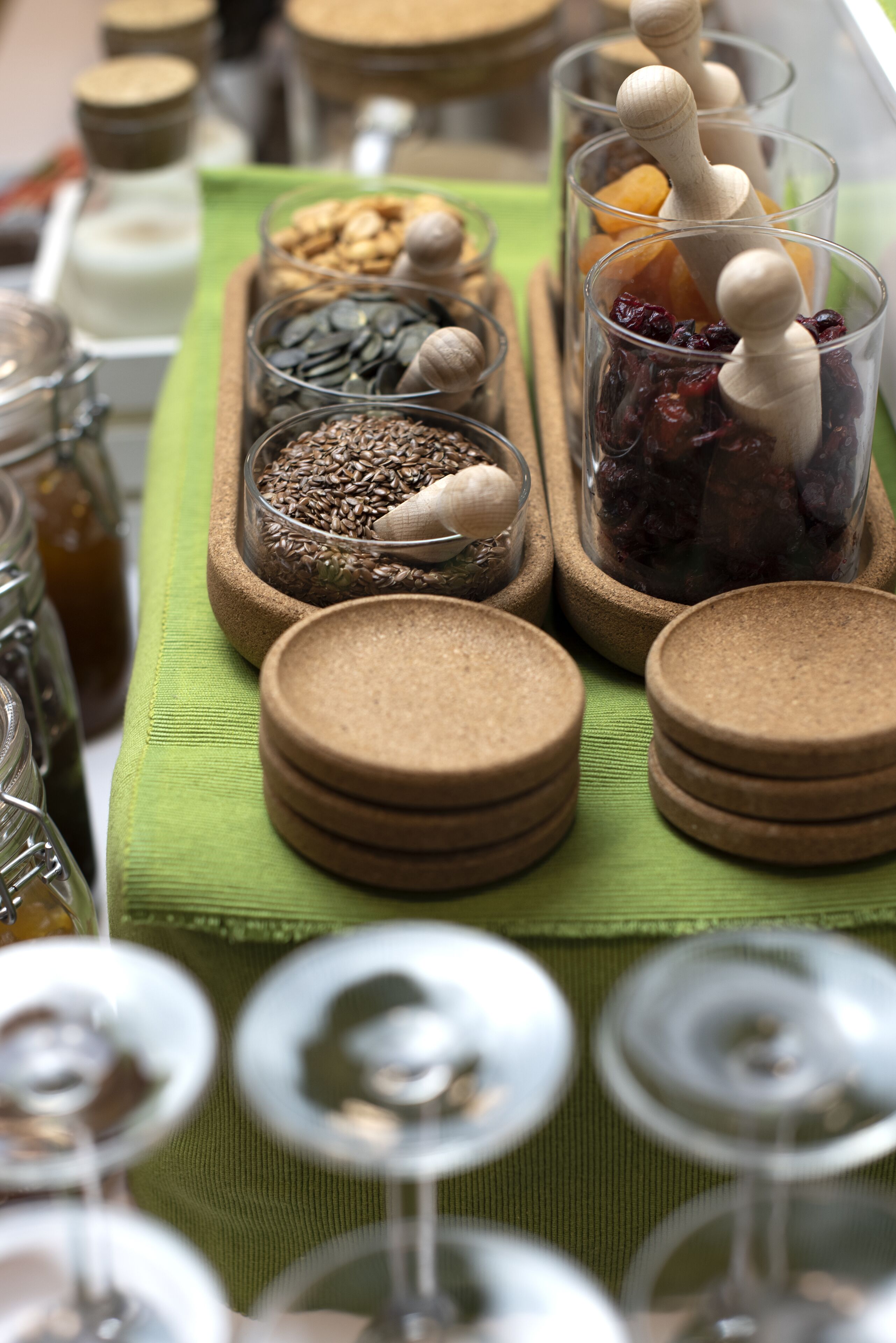 Une table sur laquelle sont disposés divers aliments et récipients, notamment des bocaux et des verres accompagnés de cuillères en bois.