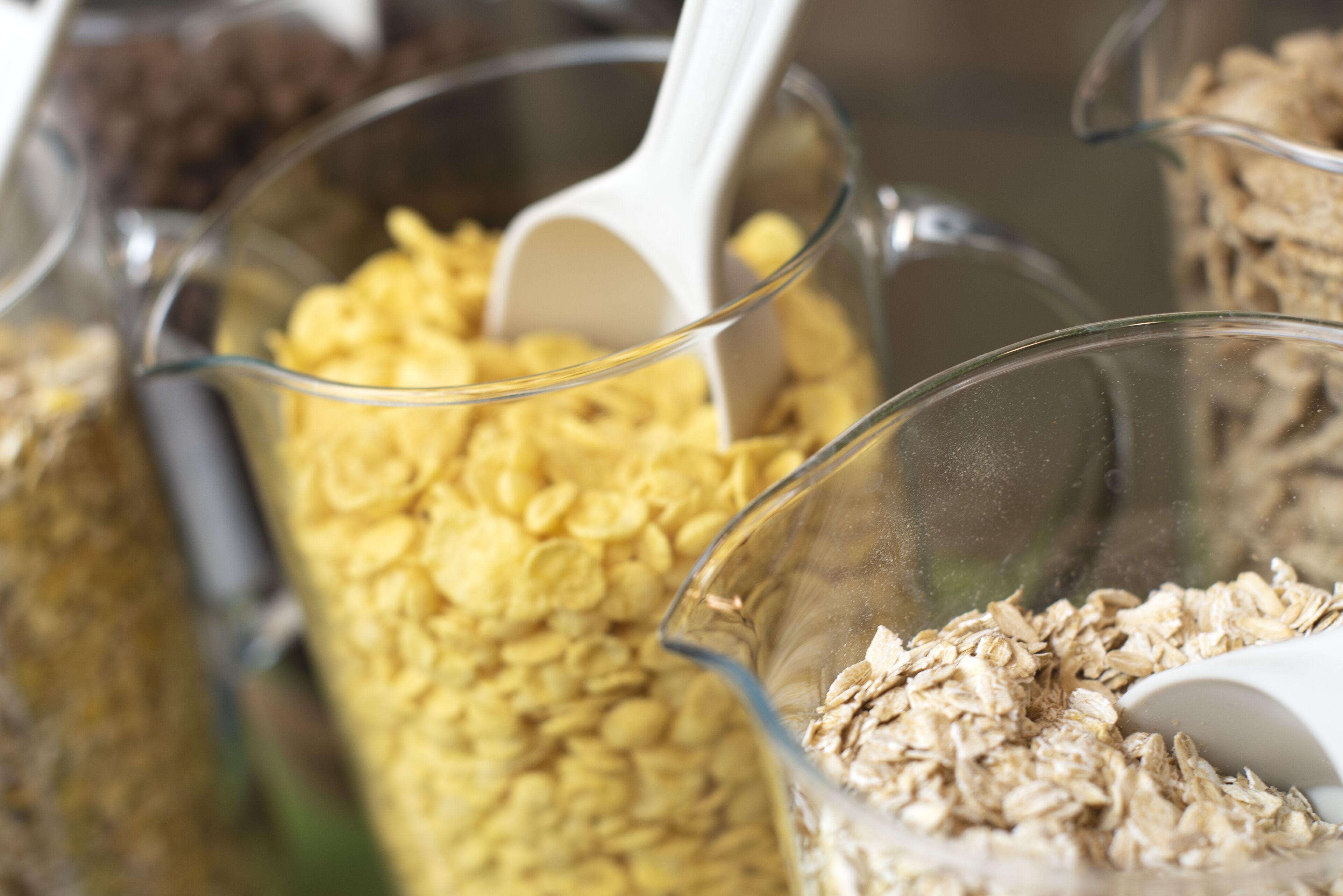 Primer plano de diversos granos y cereales en tazas medidoras transparentes.