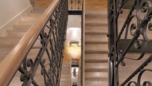 Een trap met sierlijke metalen leuningen en een houten handrail, leidend naar een plateau met een decoratief muurdecoratie.