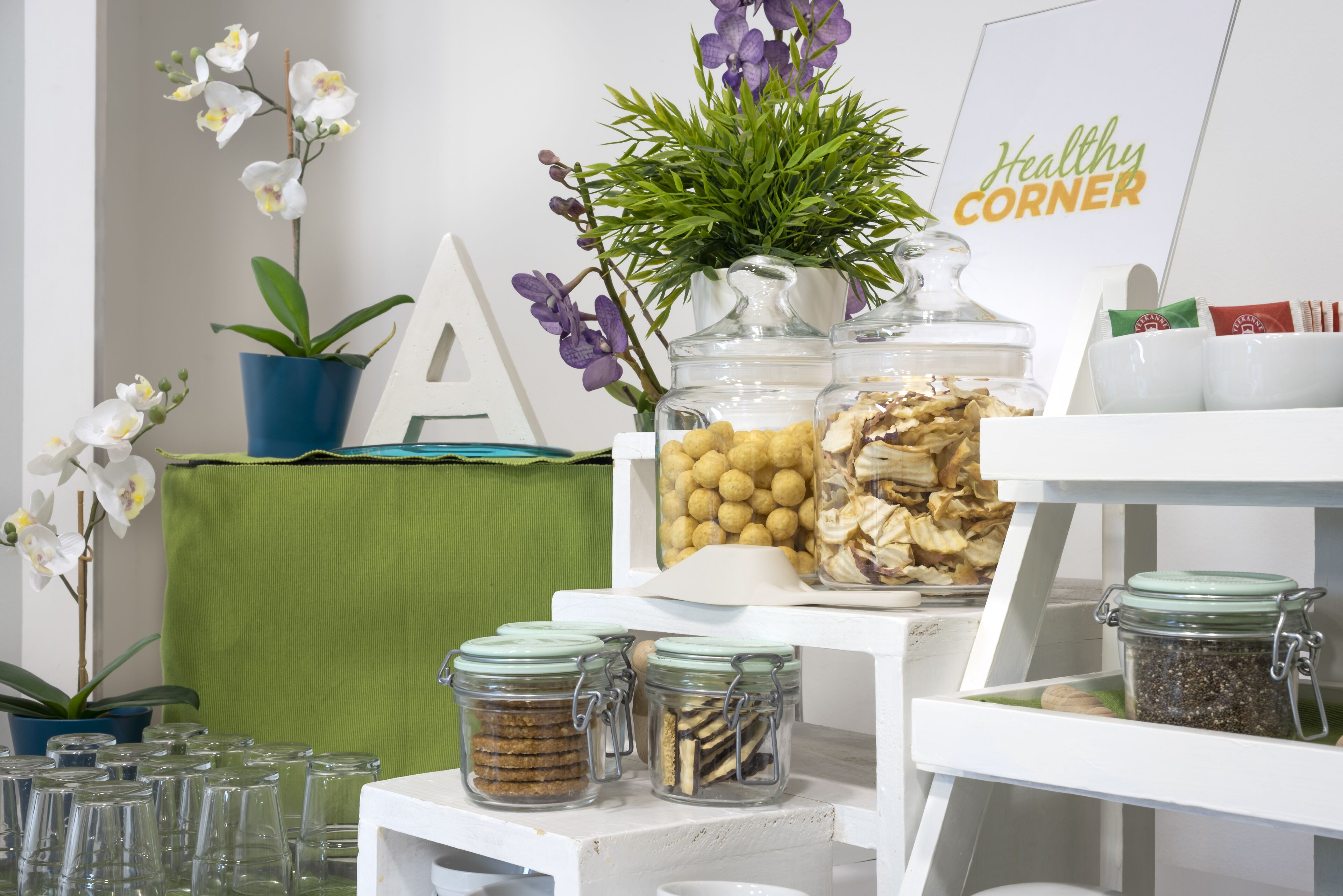 A kitchen counter with jars of food, a potted plant, and a sign that reads "Healthy Corner".