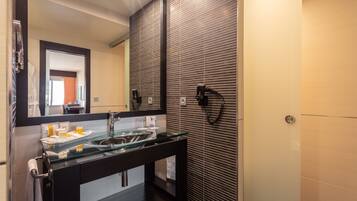 Un baño moderno con un lavabo de vidrio, muebles oscuros y un espejo grande.