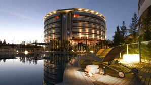 Un hotel moderno con diseño circular, piscina y tumbonas.