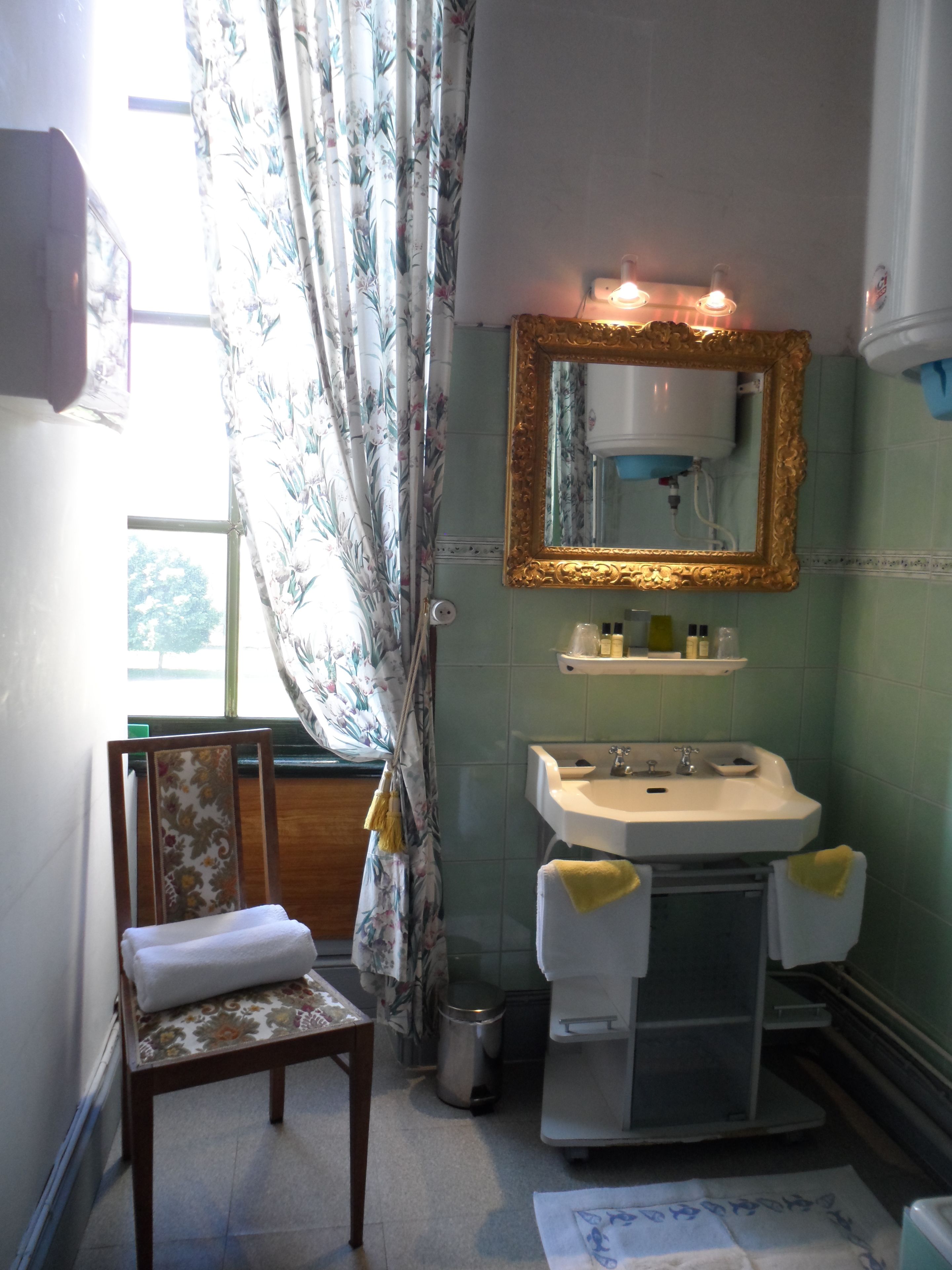 Ein Badezimmer mit Waschbecken, Spiegel und Stuhl.