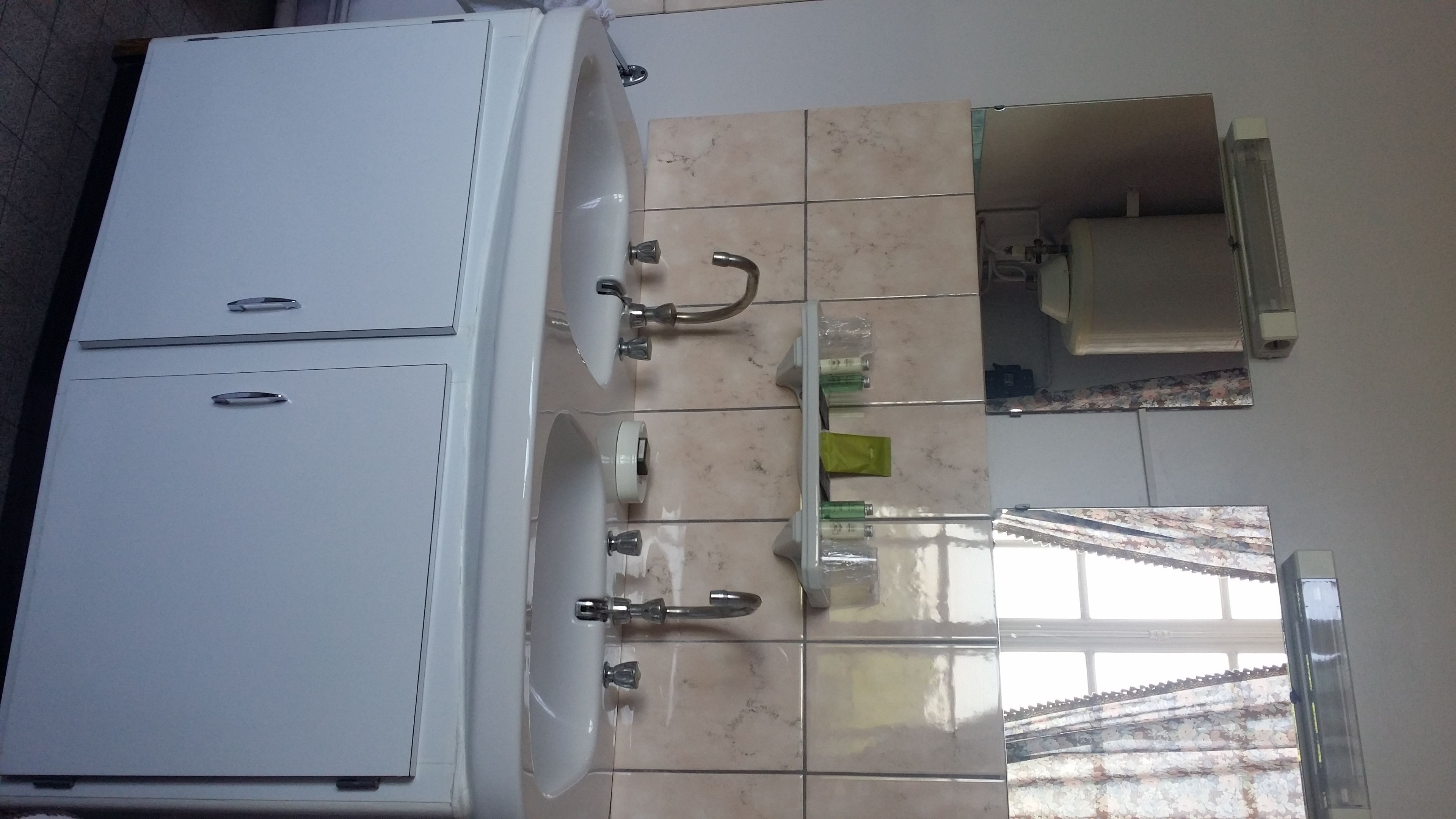 A bathroom with a white cabinet, a sink with a mirror, and a tiled floor.