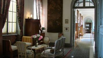 A room with a large window, a wooden cabinet, a painting, and a chair.