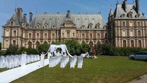 A large, historic building with a formal outdoor wedding setup in front.