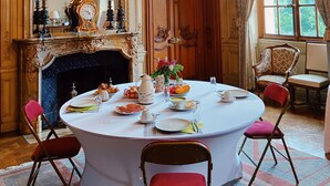 A luxurious room with a round table set for dining, ornate chandeliers, and a large mirror.