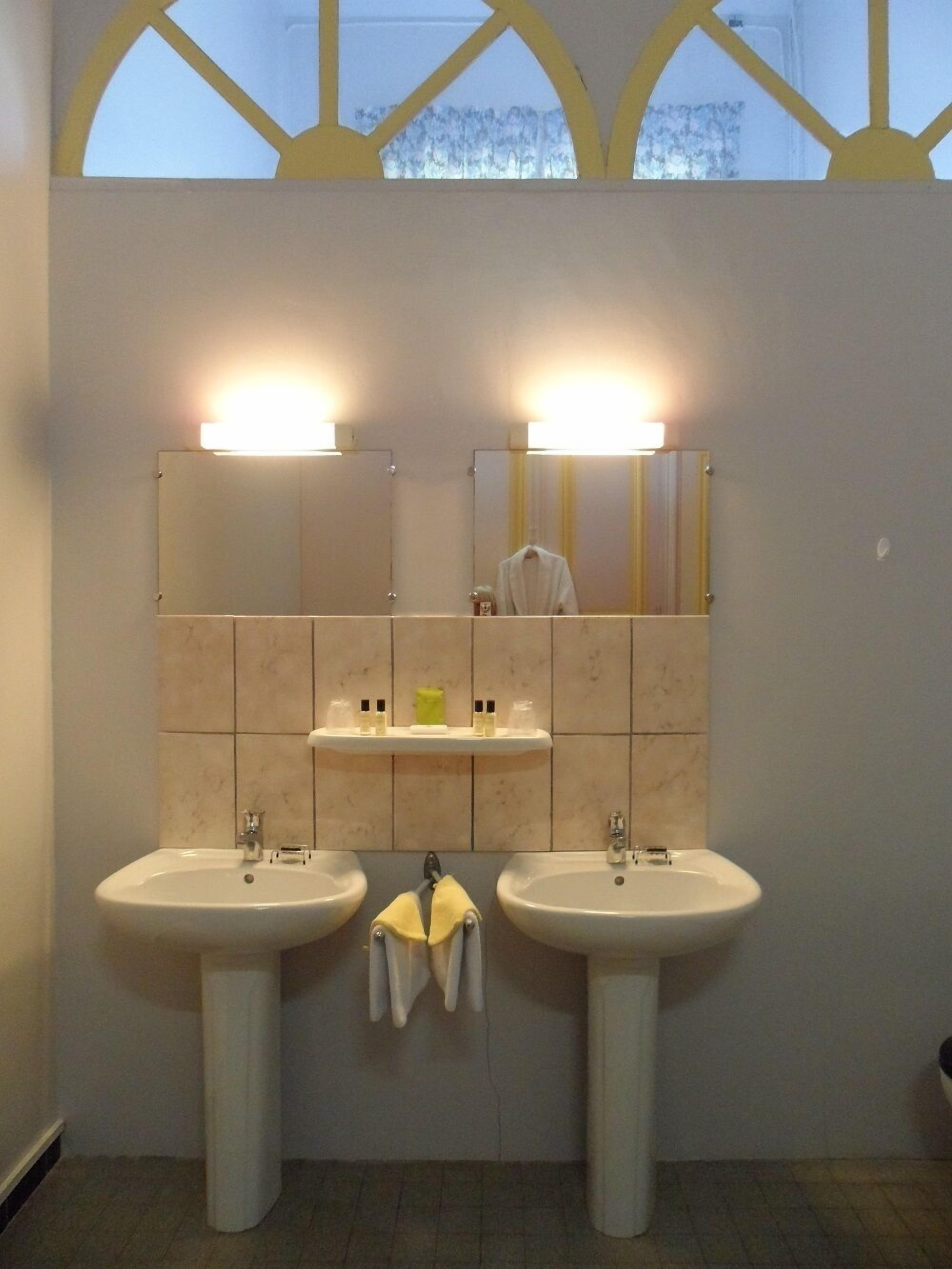 A bathroom with two sinks, a mirror, and a towel rack.
