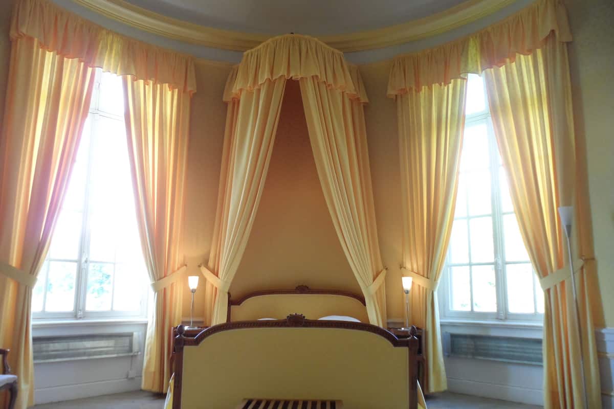 Quarto com uma cama grande, cortinas e uma janela.