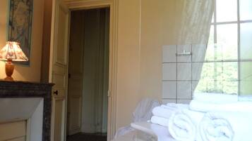 A bathroom with a sink, towel rack, and a window with curtains.