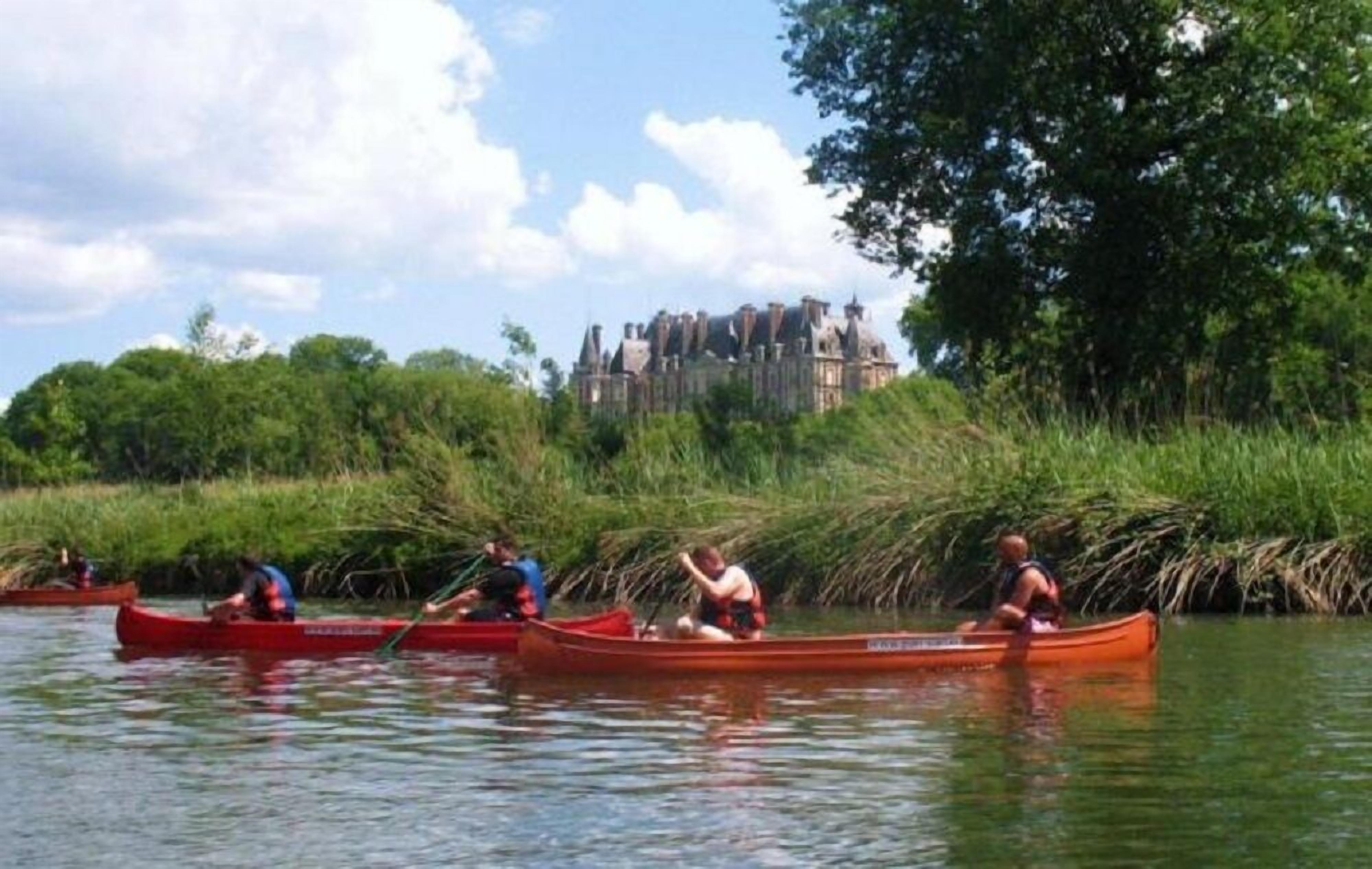 Botes piragua en un río tranquilo con un edificio histórico al fondo.