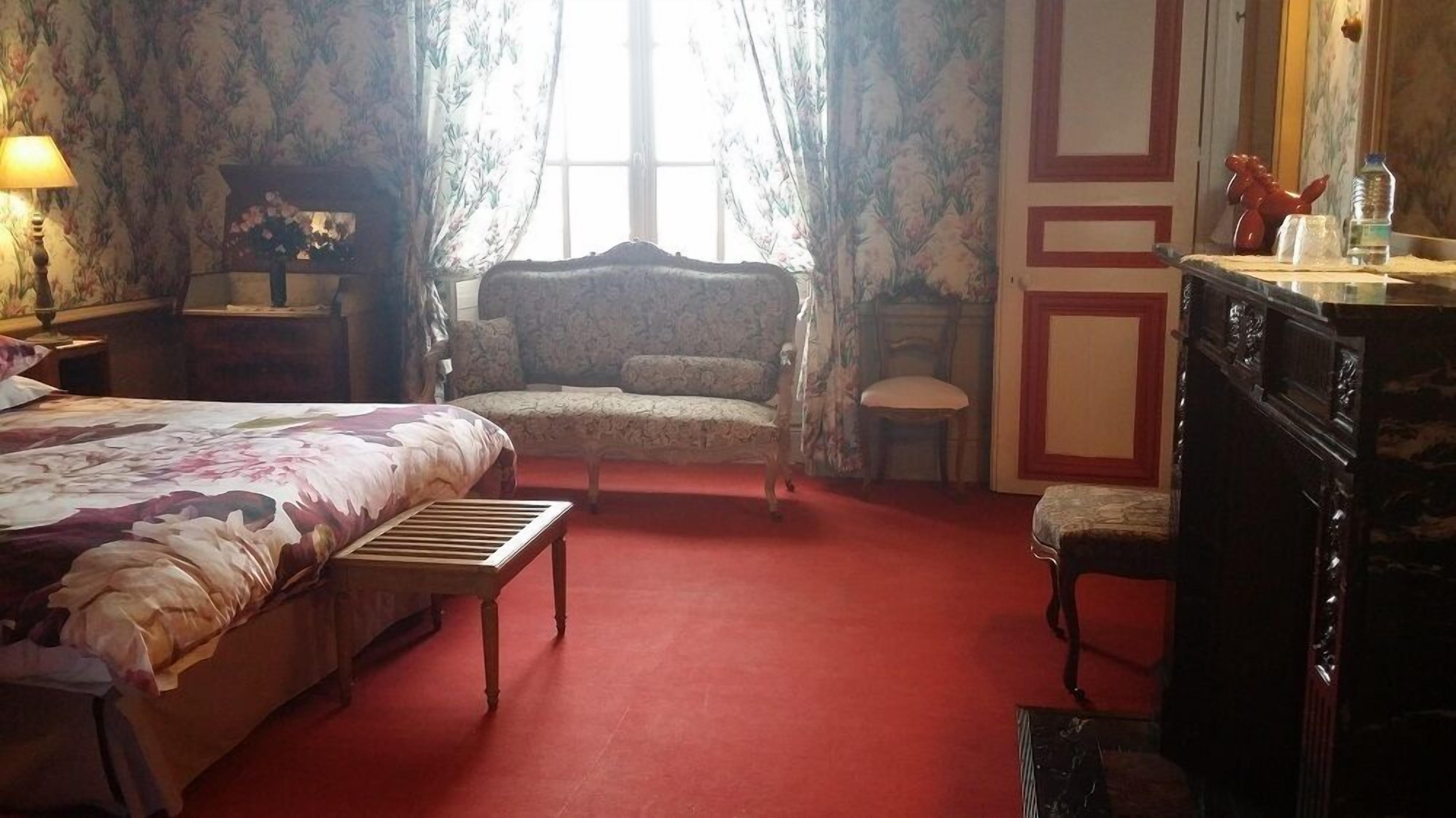 A bedroom with a bed, a chair, a small table, and a dresser.