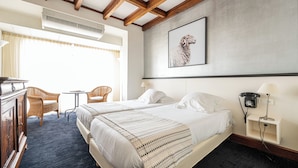 A hotel room with two beds, a desk, a chair, a small table, and a wall-mounted telephone. - Hôtel Ithurria (Ainhoa)