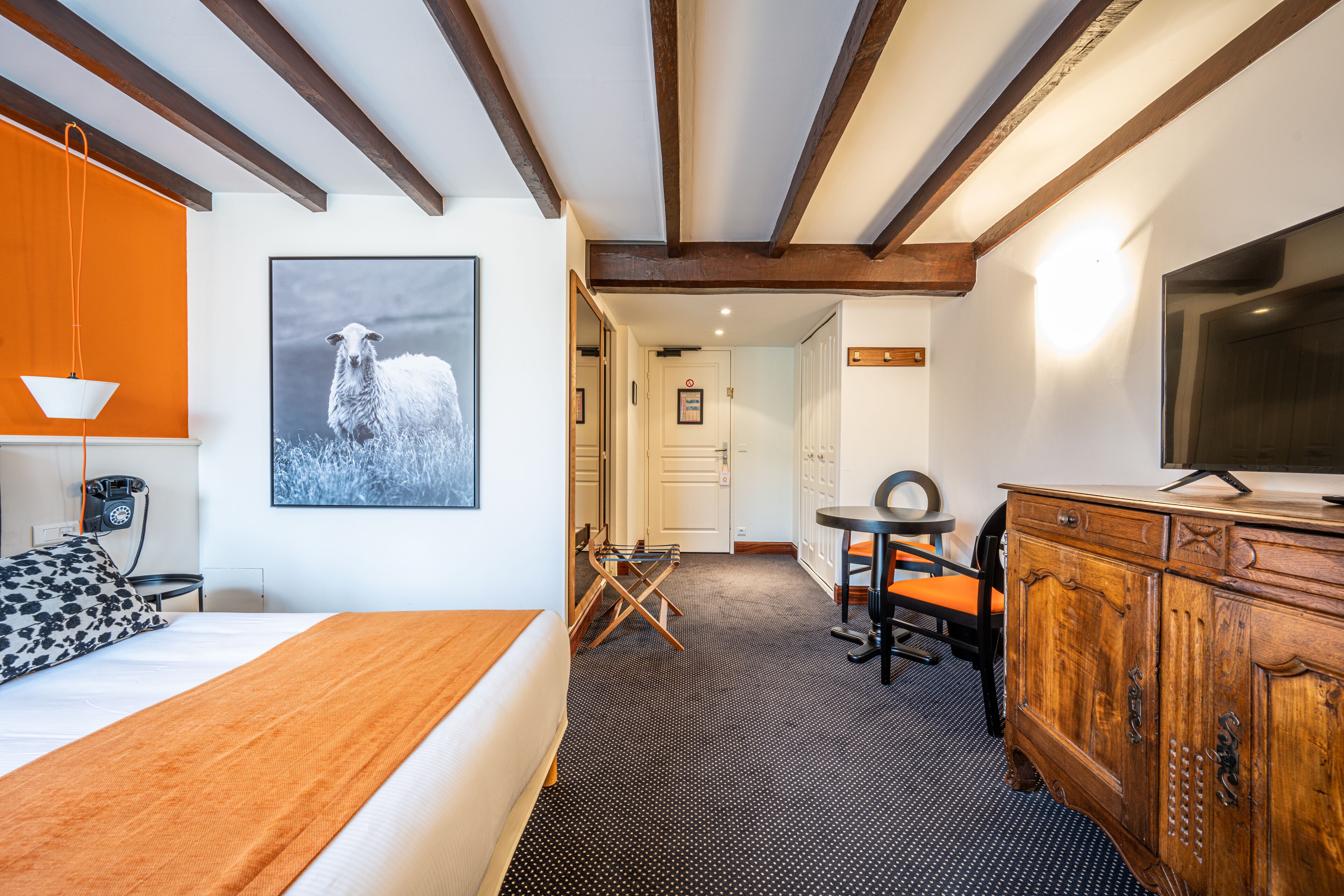 A hotel room with a bed, a desk, a television, and a wooden cabinet.