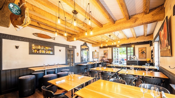 A restaurant with wooden tables and chairs, hanging light fixtures, and a fish mounted on the wall. - Hôtel Ithurria (Ainhoa)