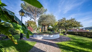A stone pathway leading to a circular garden with a lamppost and trees. - Hôtel Ithurria (Ainhoa)