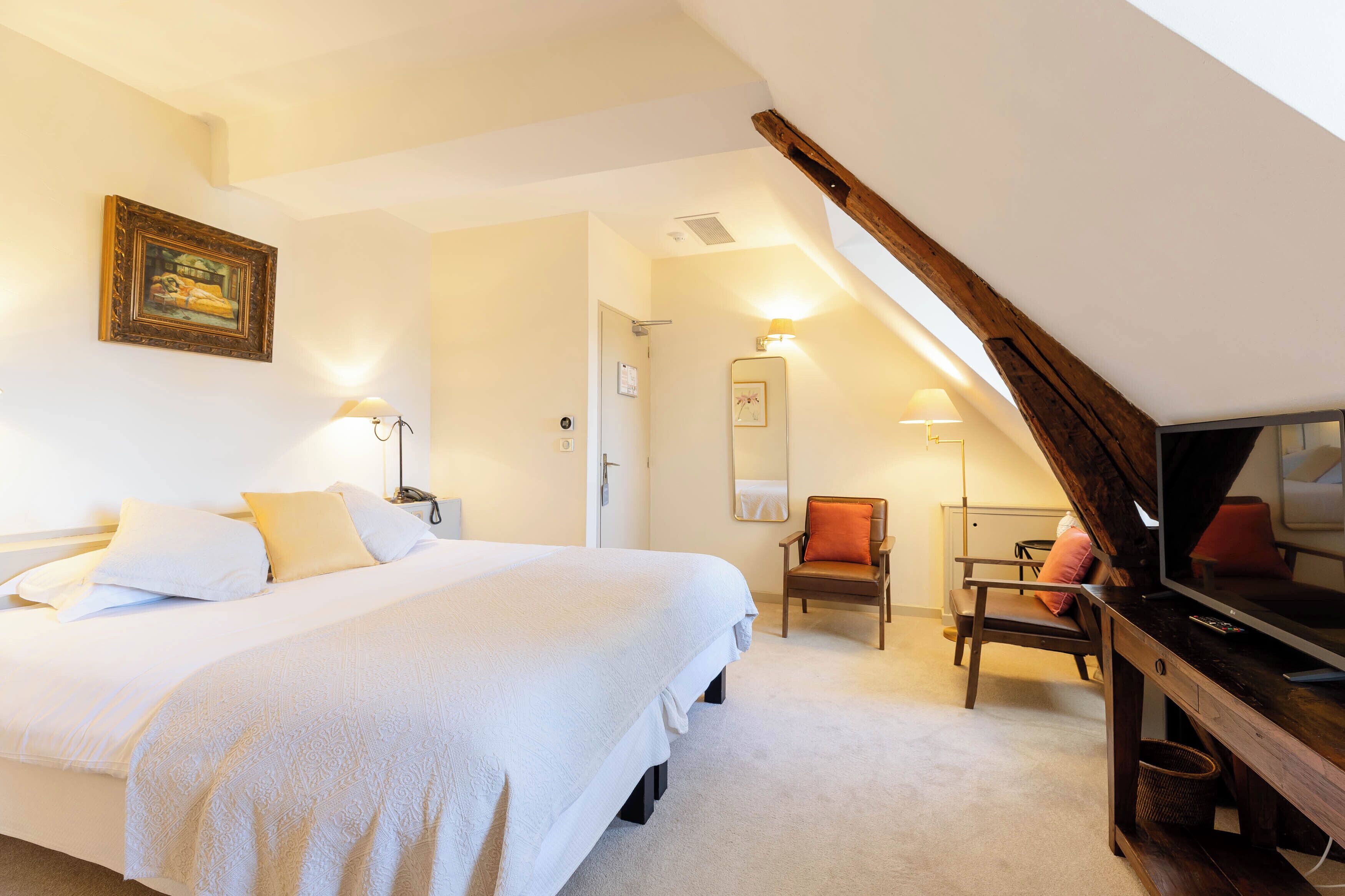 Une chambre à coucher avec un lit, une chaise, une télévision et un miroir.