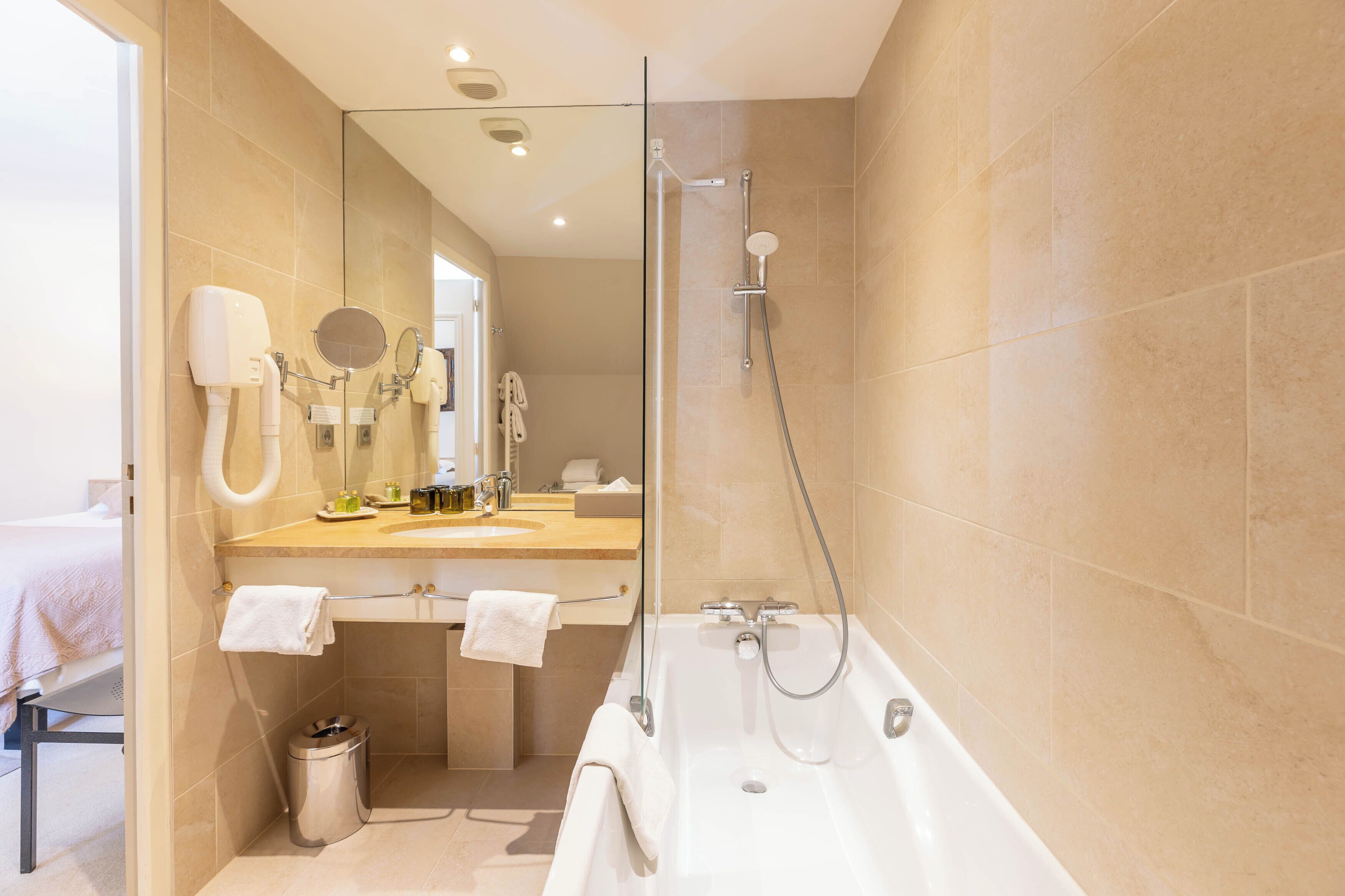 A modern bathroom with a bathtub, a shower, a vanity with a mirror, and a toilet.