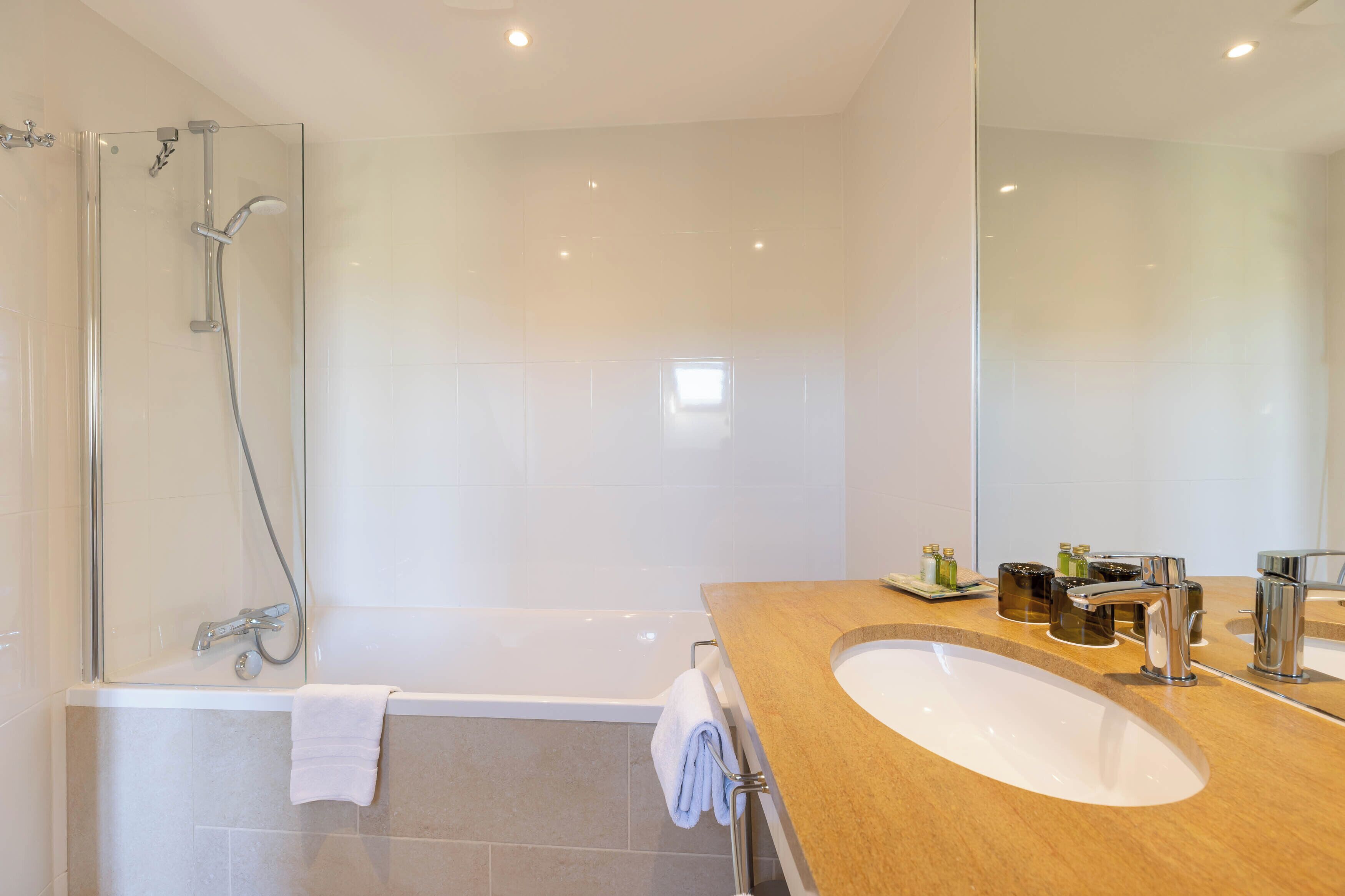 Un baño moderno con cabina de ducha de vidrio, bañera y tocador con lavabo y espejo.