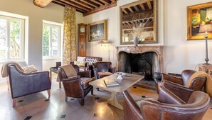 A furnished living room with leather chairs, a fireplace, and a large mirror. - Villa Louise (Aloxe-Corton)