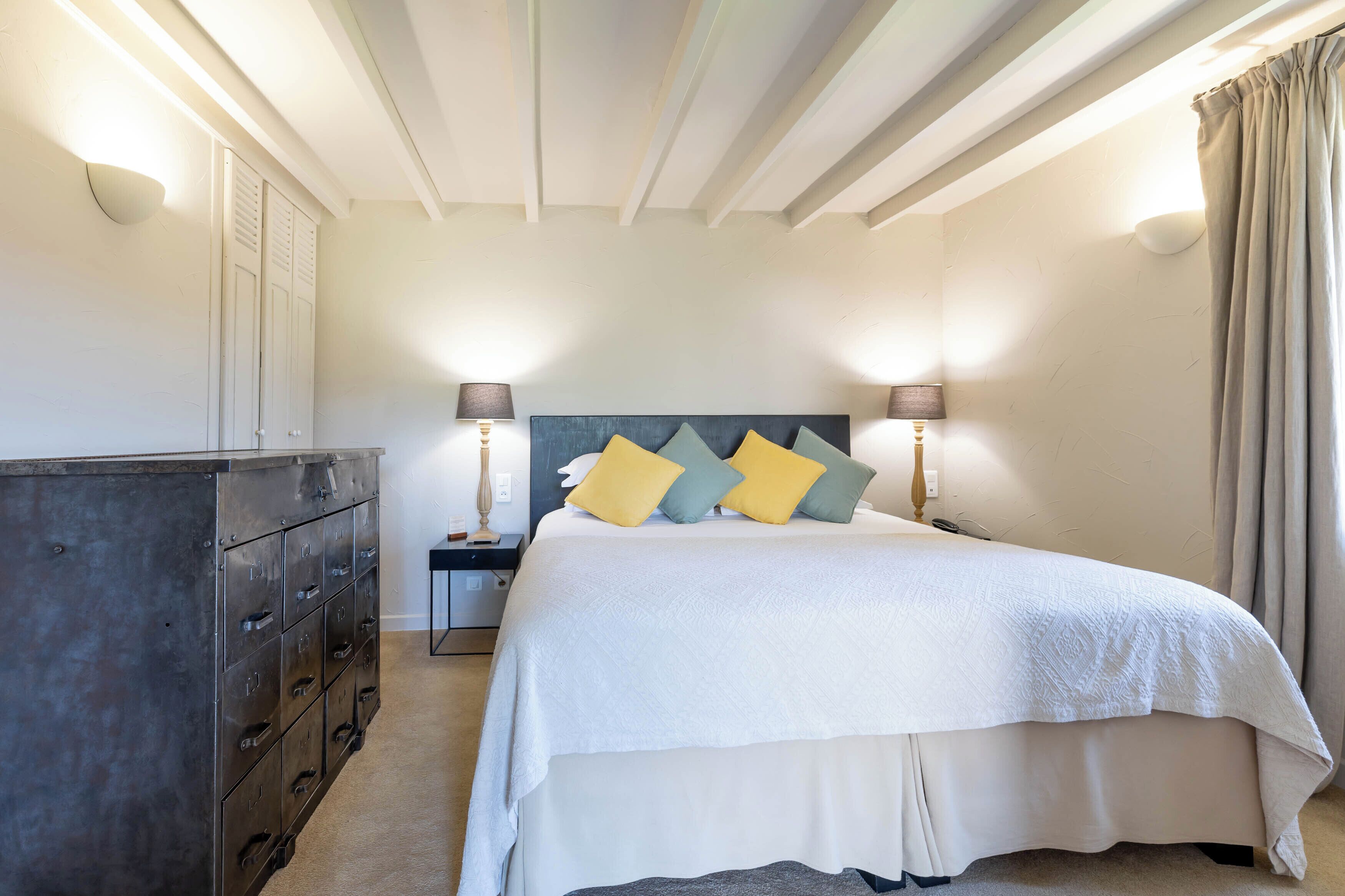 A bedroom with a bed, nightstands, a dresser, and a headboard.