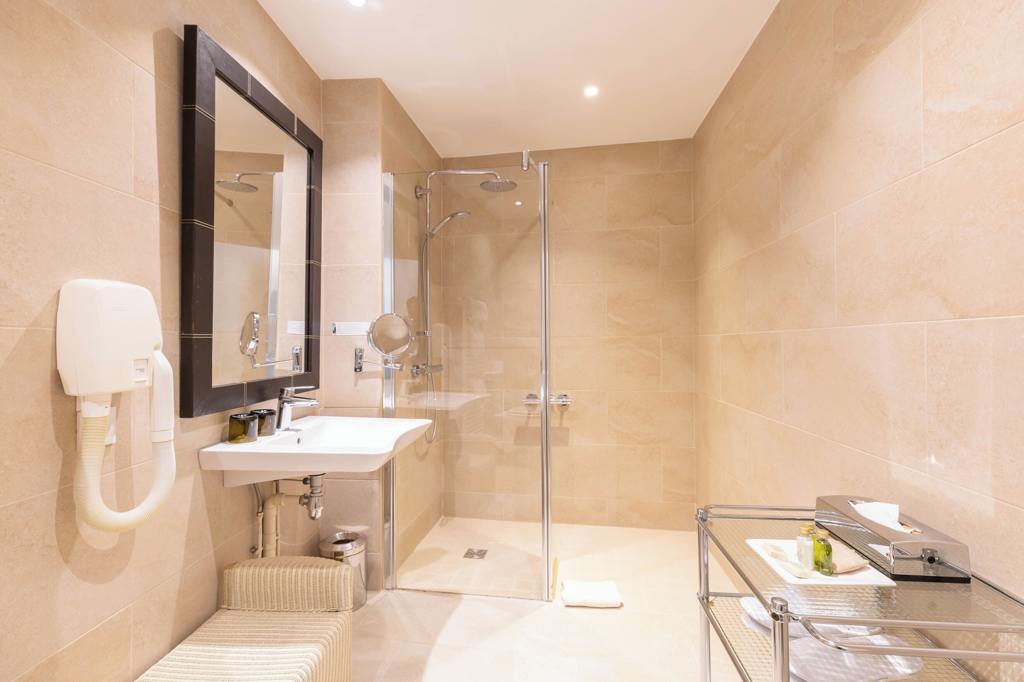 A modern bathroom with a glass shower enclosure, a white sink, and a large mirror.