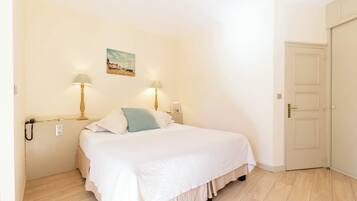 Una camera da letto con un letto, due lampade sui comodini, un quadro appeso e una porta.