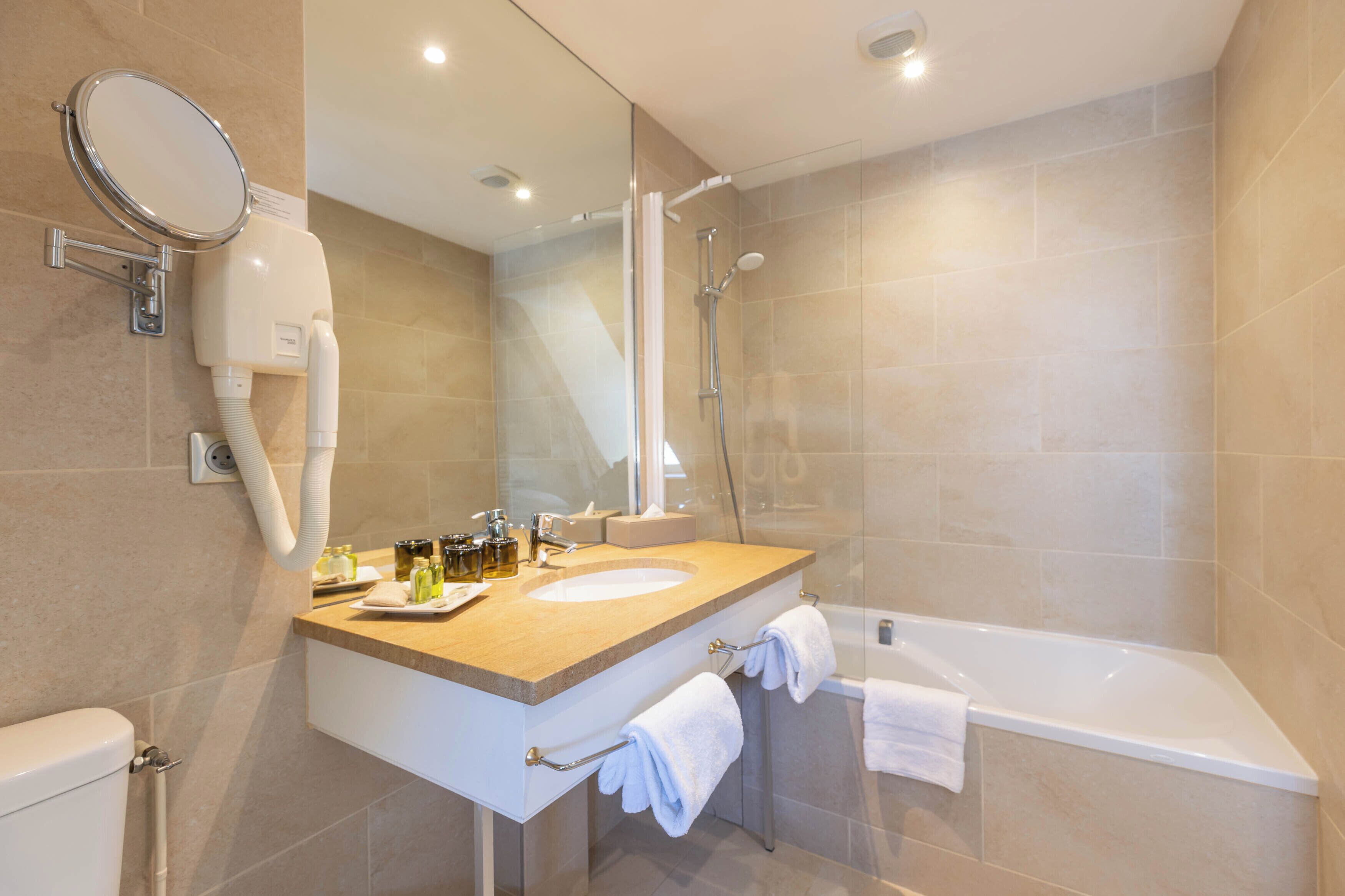 Une salle de bain moderne équipée d’un lavabo, d’un miroir, d’un porte-serviettes et d’une douche.
