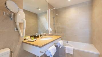 Une salle de bain moderne équipée d’un lavabo, d’un miroir, d’un porte-serviettes et d’une douche.