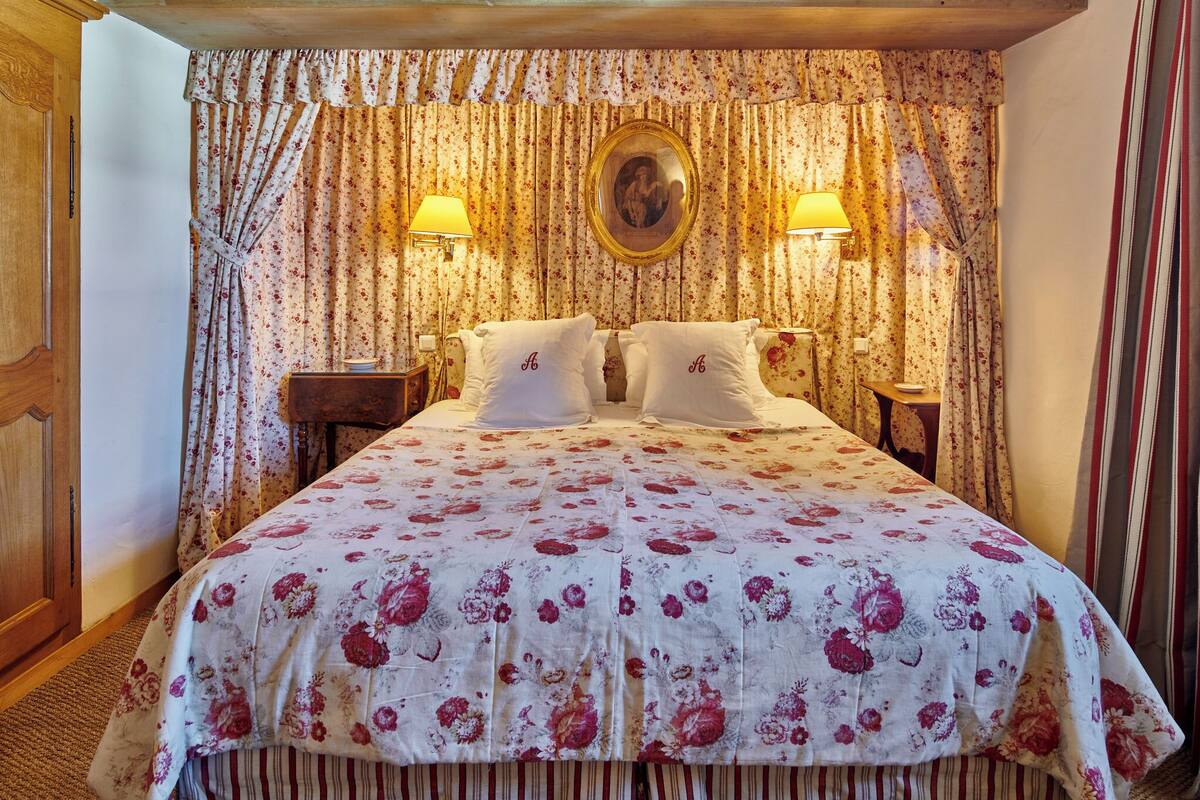 A neatly made bed with floral bedding, two bedside lamps, and a mirror above the bed.