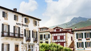 A row of traditional European buildings with balconies, some with flower boxes. - Hôtel Arraya (Sare)
