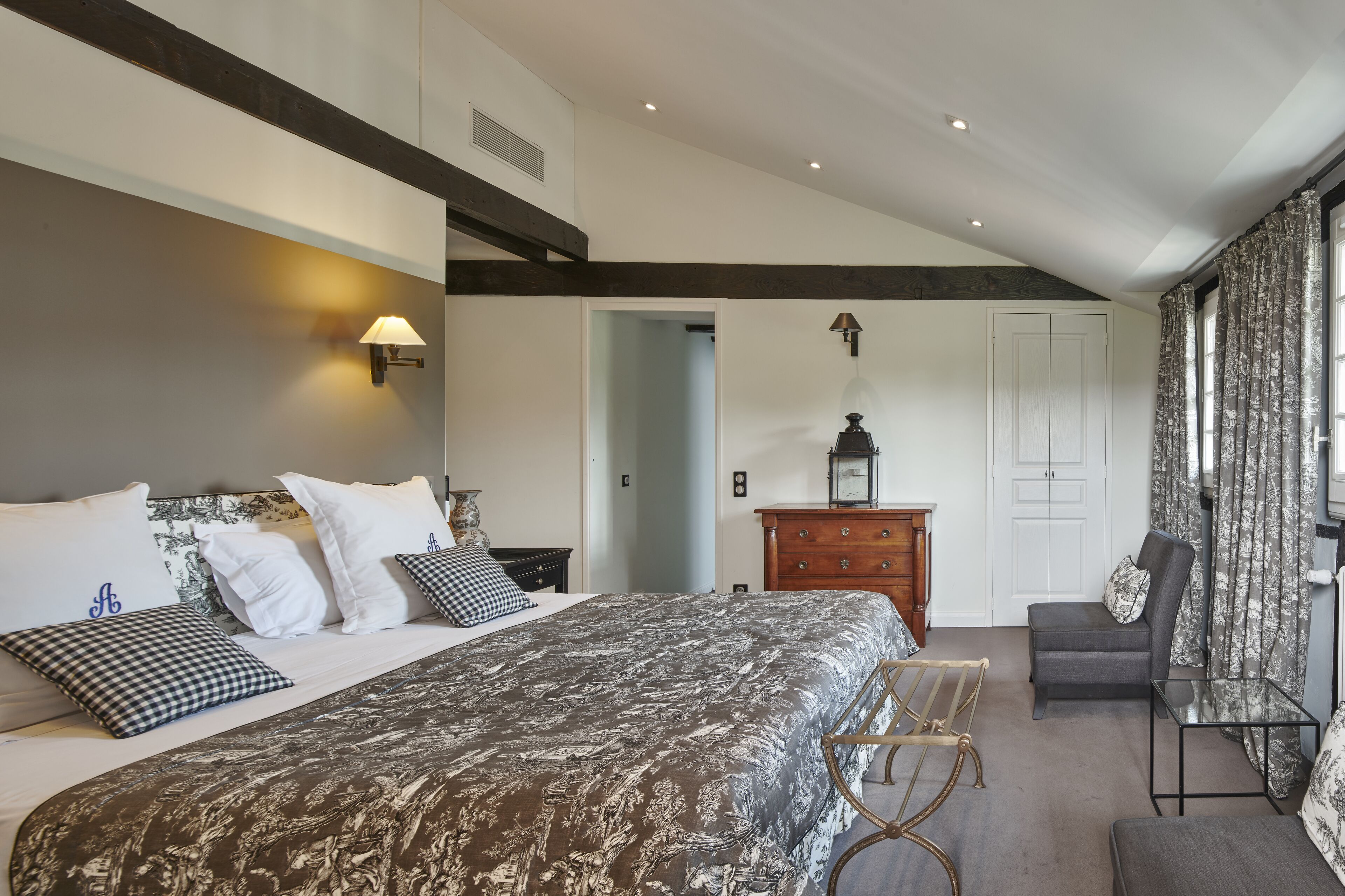 Une chambre à coucher moderne avec un grand lit, une commode, une chaise et un bureau.