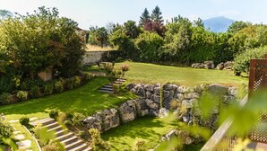 A well-maintained garden with a stone wall, a wooden deck, and a grassy lawn. - Hôtel Arraya (Sare)