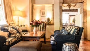 A cozy living room with a sofa, armchair, and a table with a vase of flowers. - Hôtel Arraya (Sare)