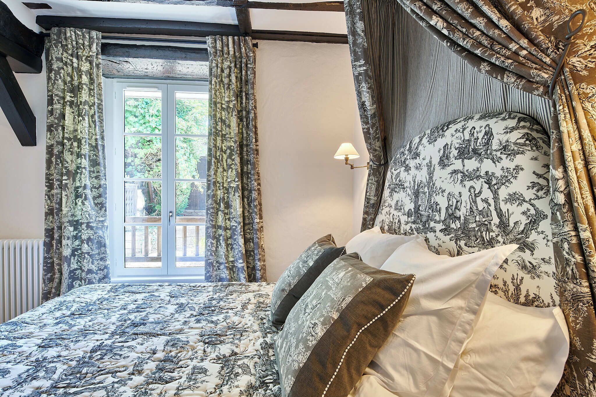 A bedroom with a bed, curtains, and a window with a view.