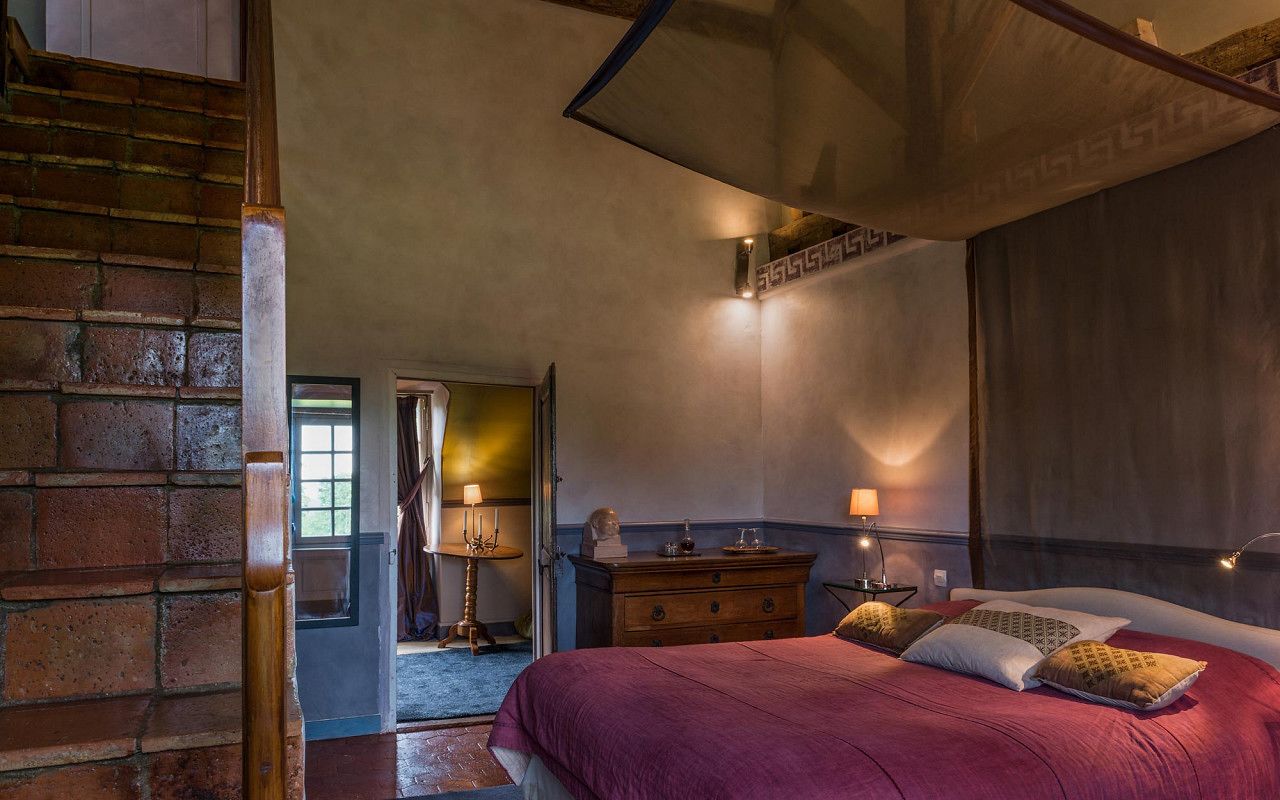 Un dormitorio con una cama grande, cómoda de madera y una escalera.