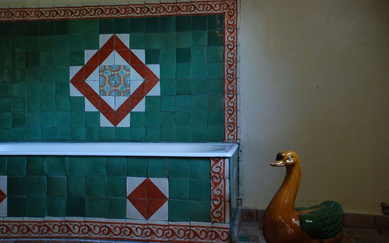 A tiled wall with a geometric pattern and a decorative swan statue.