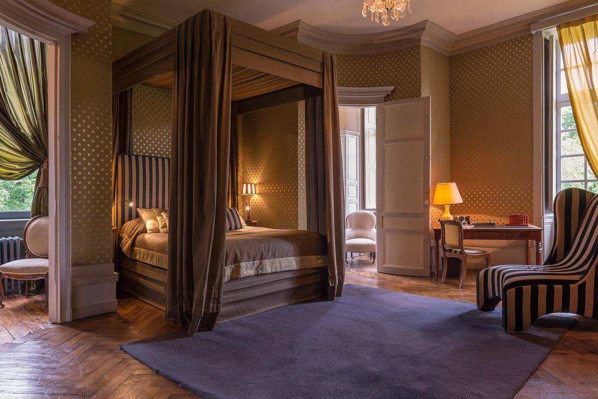 Een slaapkamer met een hemelbed, een bureau met stoel, en uitzicht op de omgeving.