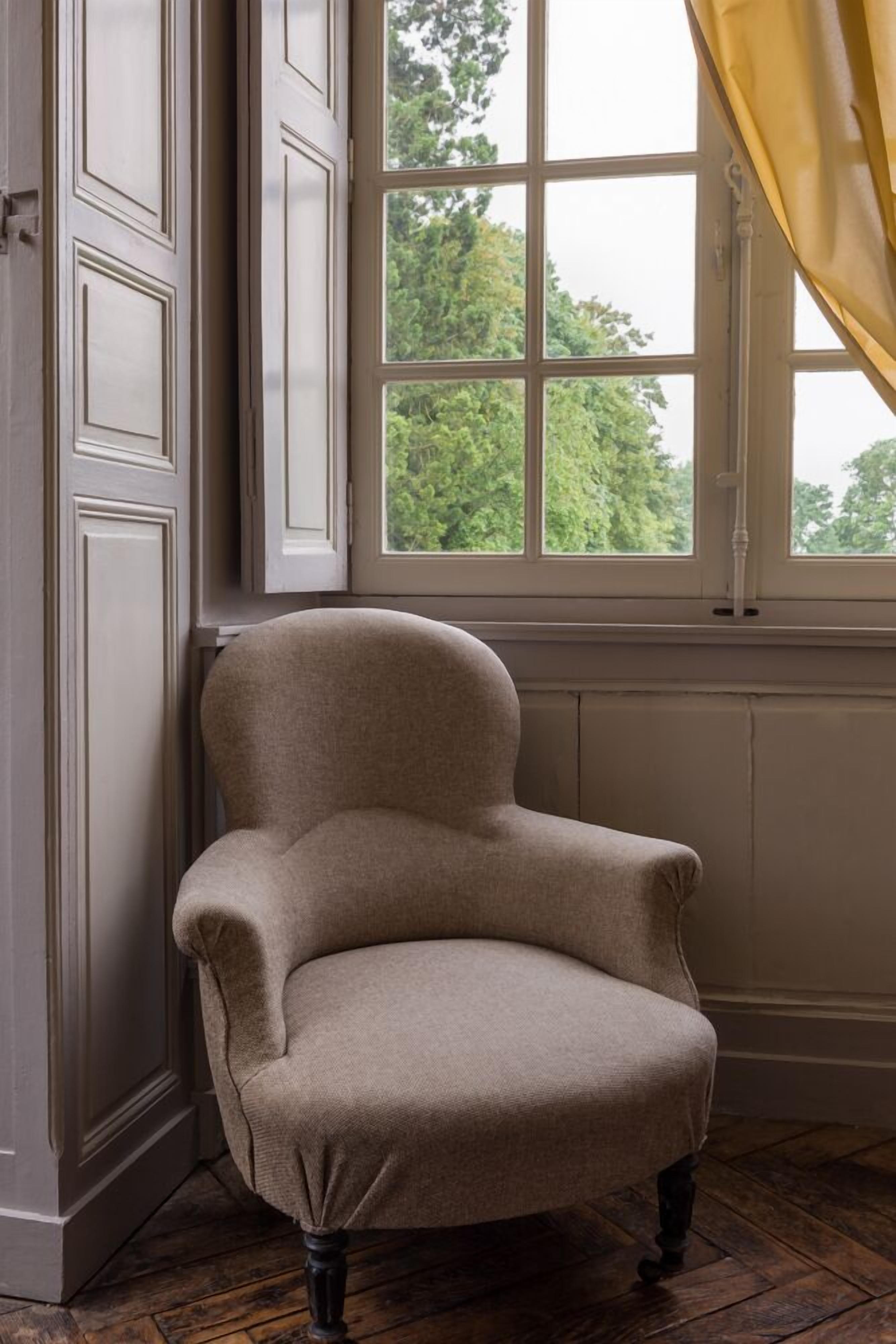 A chair in a room with a window, wooden floor, and a door with paneling.
