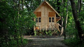 Una cabaña de madera con balcón, rodeada de un bosque denso.