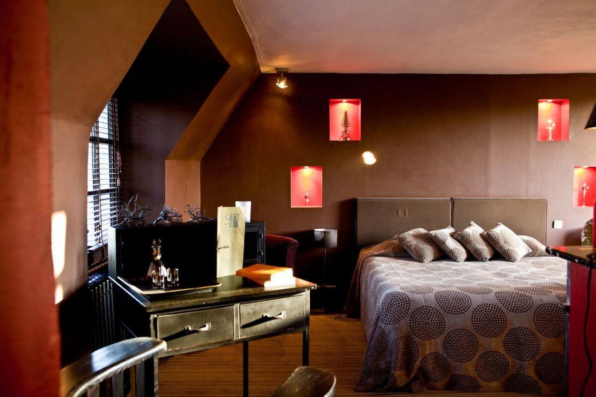Een knus slaapkamer met een groot bed, een bureau met stoel en een raam met zonwering.