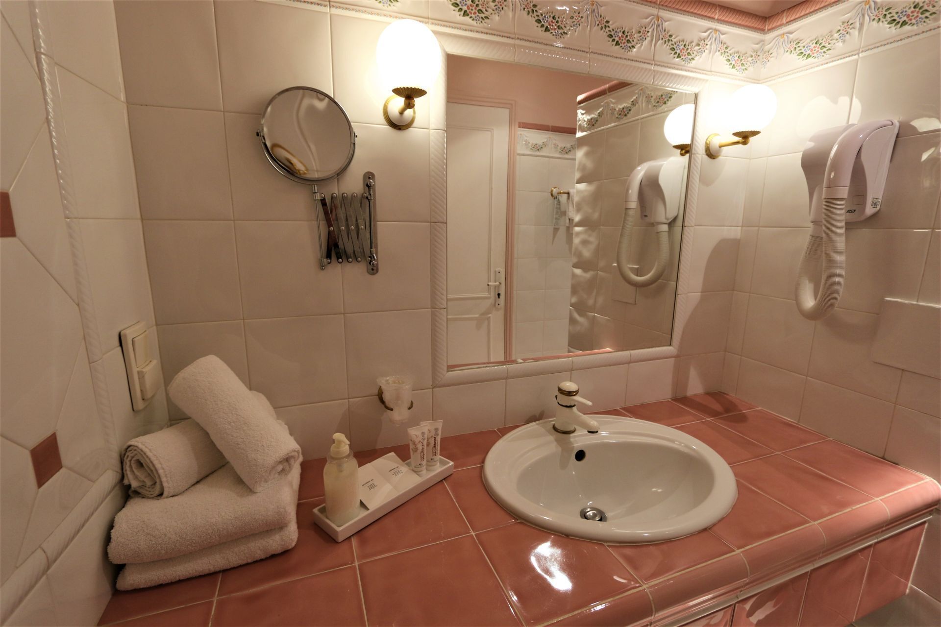 Une salle de bain équipée d’un lavabo, d’un miroir, d’un porte-serviettes et d’articles de toilette.