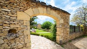 A stone archway leading to a stone pathway. - Hôtel de la Ferme Lamy (Meyrals)