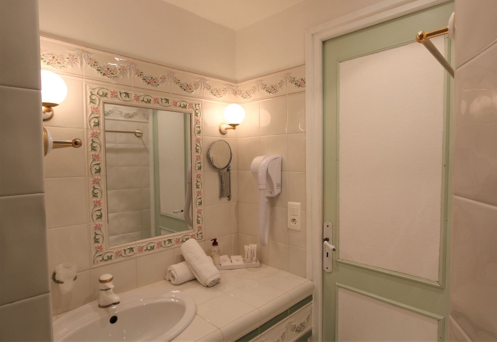 A bathroom with a sink, mirror, towel rack, and a door with a towel hanging on it.