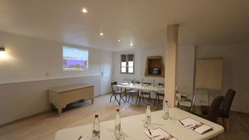 A conference room with a long table, chairs, a projector screen, and a whiteboard.