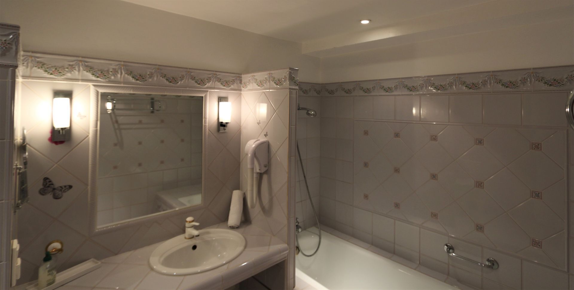 A bathroom with a sink, mirror, shower, and toilet.