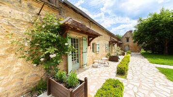 A stone building with a garden patio, wooden benches, and a stone pathway.