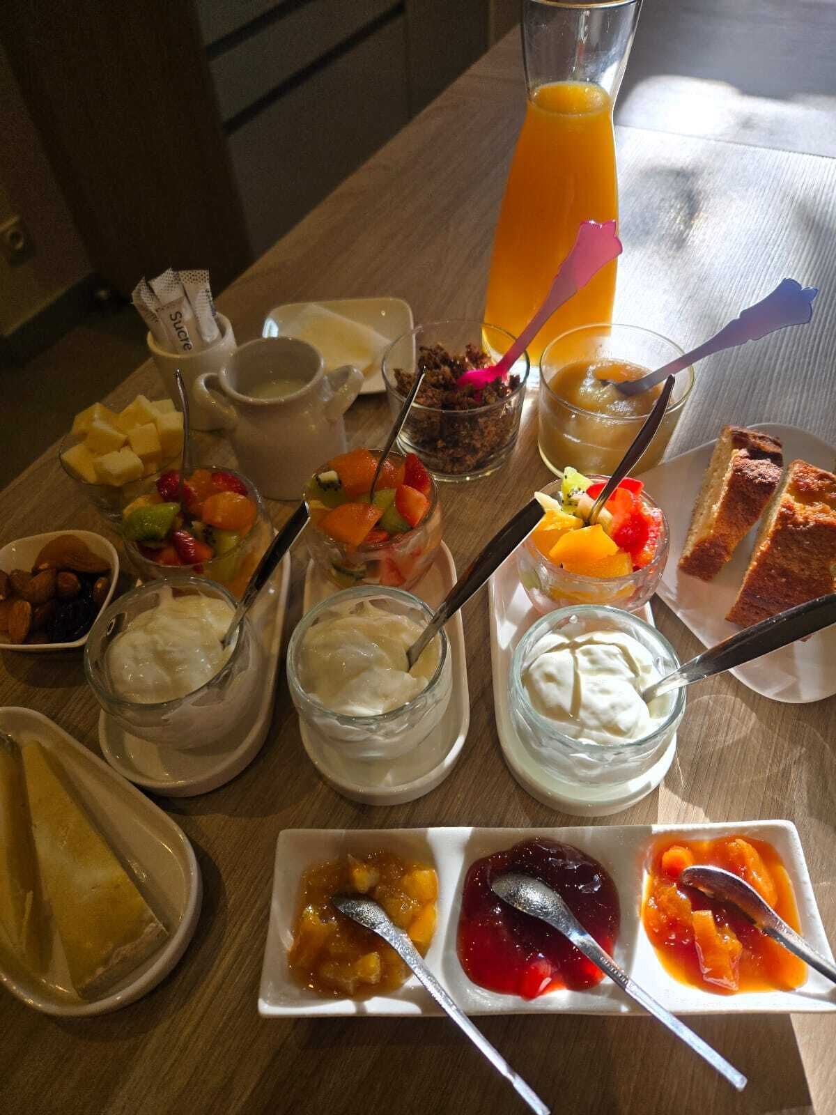 A breakfast table with various food items including fruits, yogurt, and toast.