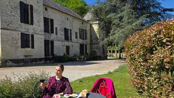 A woman sitting at a round table outdoors with a building in the background.