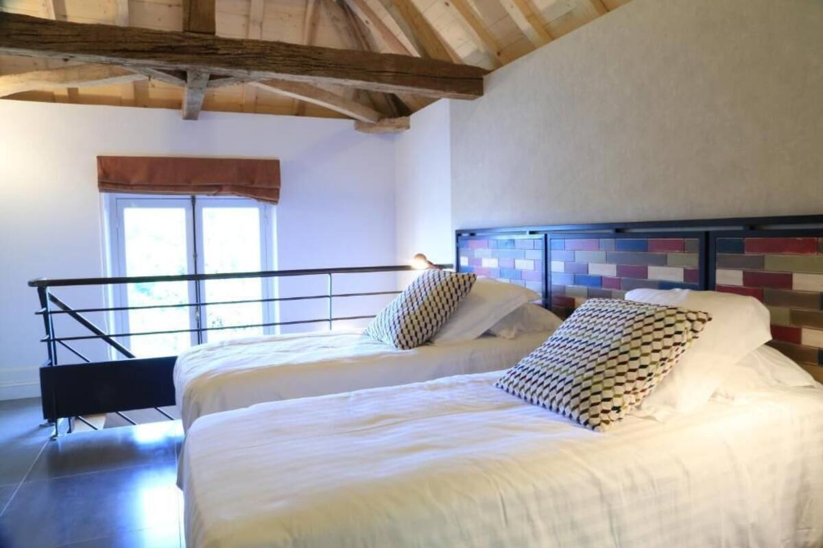 A bedroom with two beds, a window with a view, and a wooden ceiling.